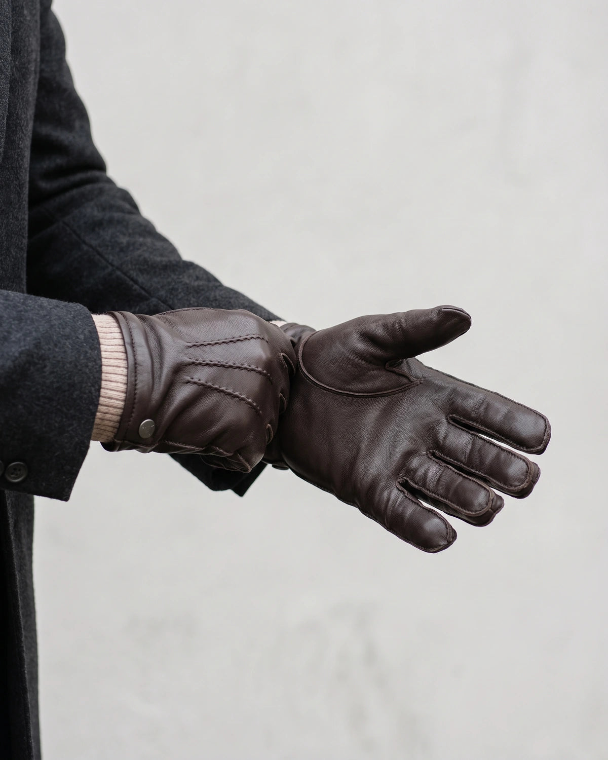 Herrenhandschuhe: dunkelbraune Lederhandschuhe mit Strickbund werden angezogen